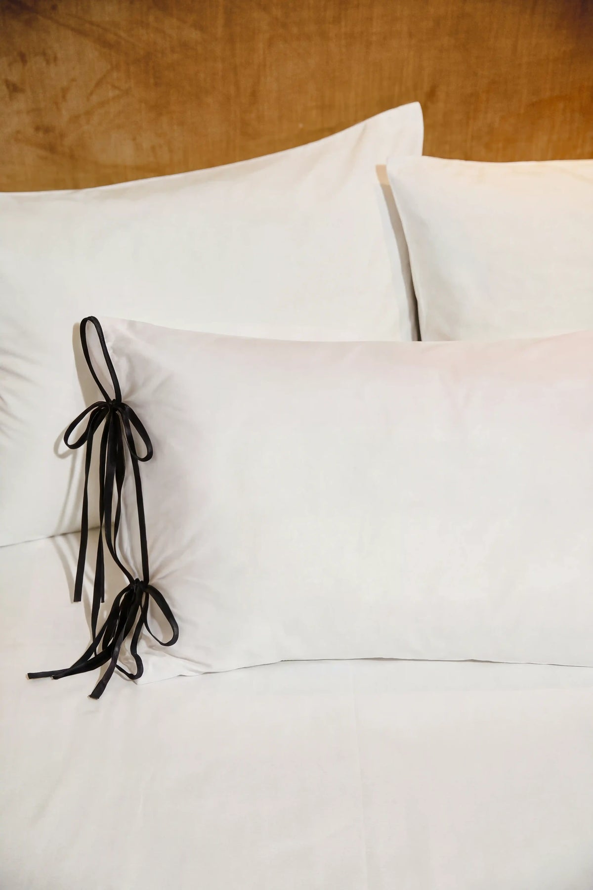 Camille Ribbons Satin Pillowcase in Black featuring delicate ribbon details and a luxurious satin finish
