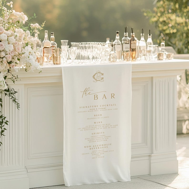 White bar setup with floral decorations and a 'The Bar' sign in an outdoor setting.